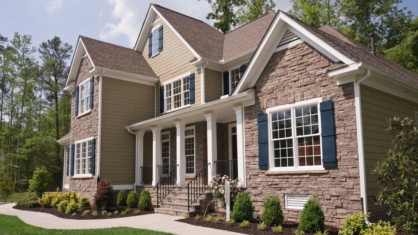 Brown shingle roof over a two-story home with stacked stone and shake siding