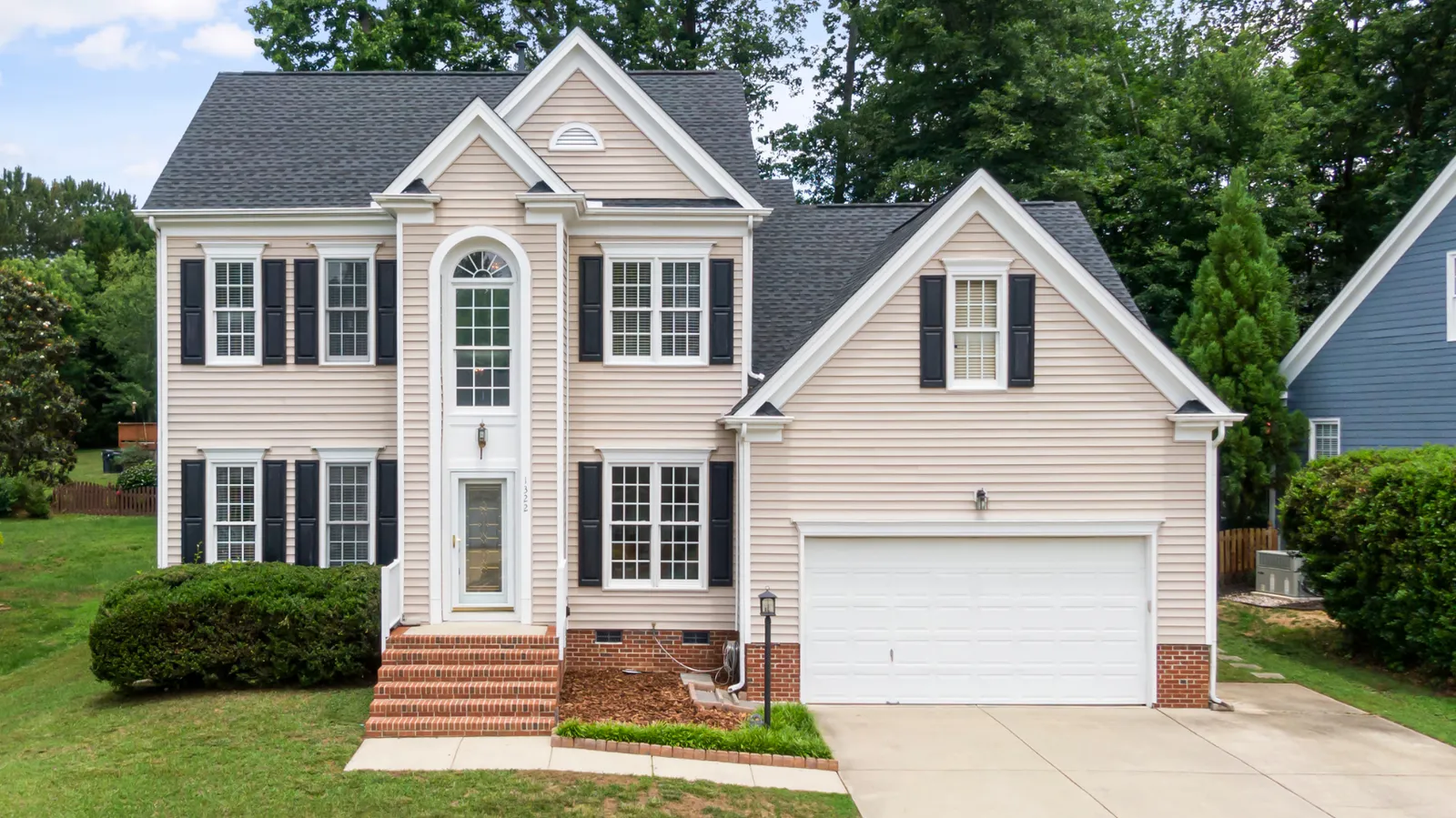 Dark shingle roof and black shutters on a beige two-story home
