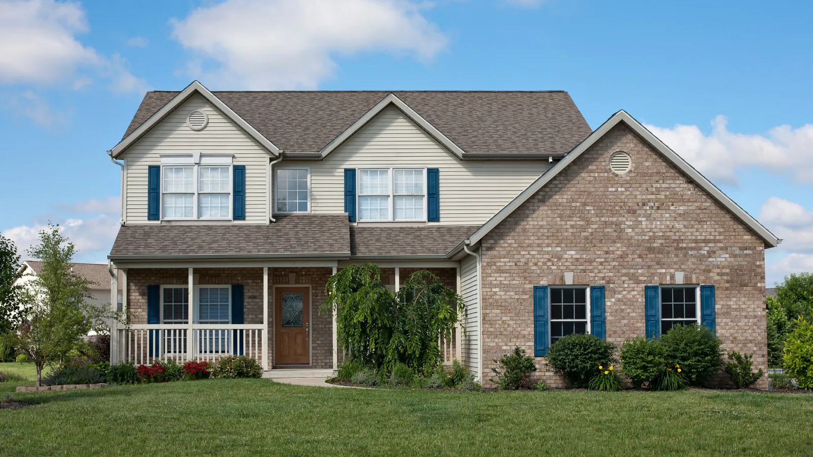 Brown shingle roof on a brick and siding two-story home