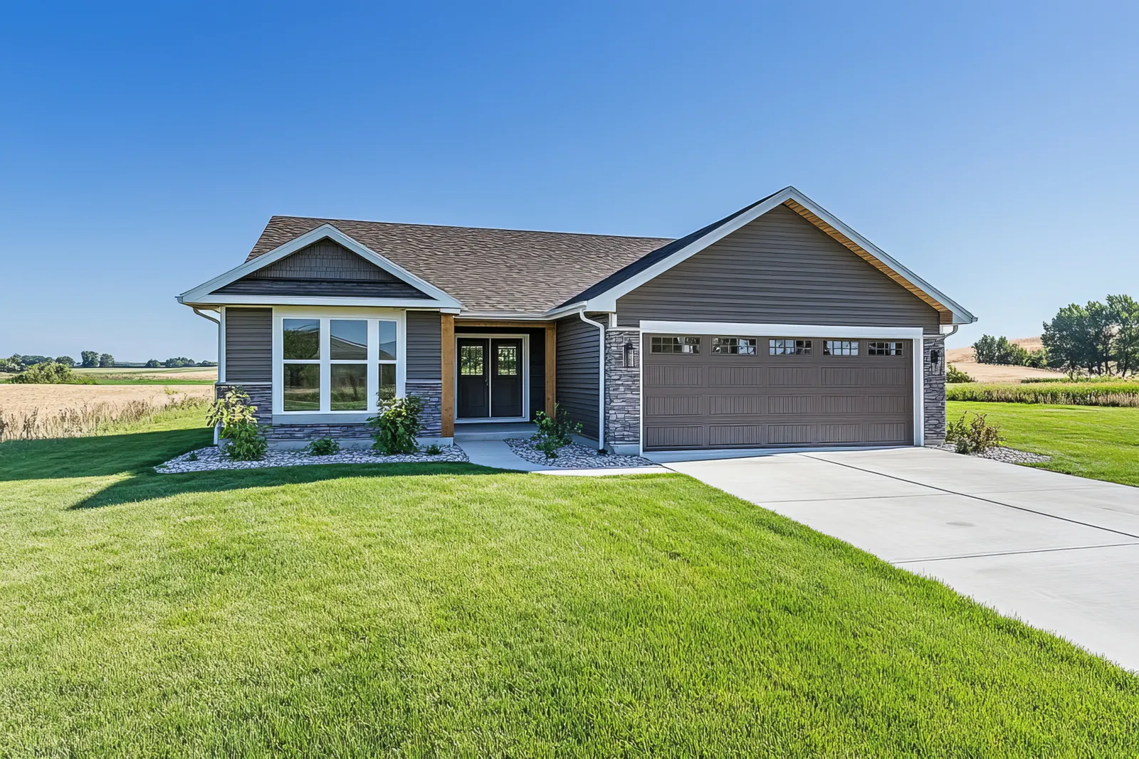 Stone accented garage on a ranch home under a brown shingle roof