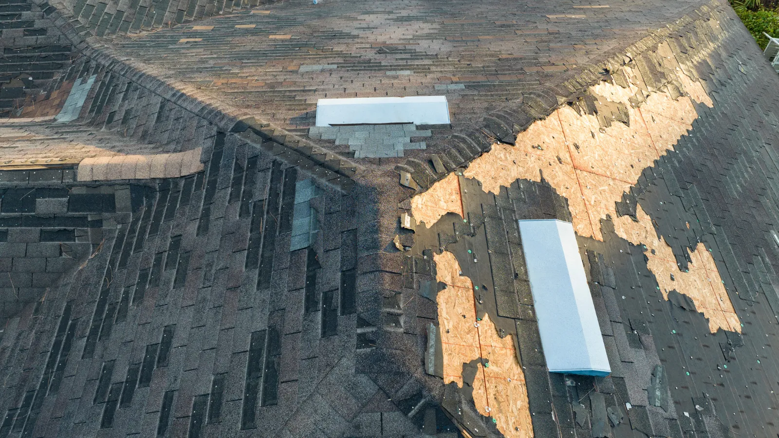 Aerial view of exposed plywood patches beside skylights on a roof